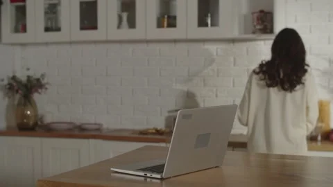 Brunette woman with computer dancing in the kitchen. Remote work on laptop Stock Footage 232804269