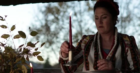 Brunette woman in pattern jacket put candlestick with burn red candle on table Stock Footage 165202721