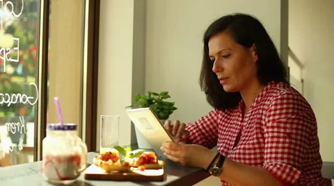 Brunette woman using tablet computer in restaurant Stock Footage 67999146