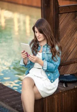 Brunette woman using tablet while sitting on bridge Stock Photos