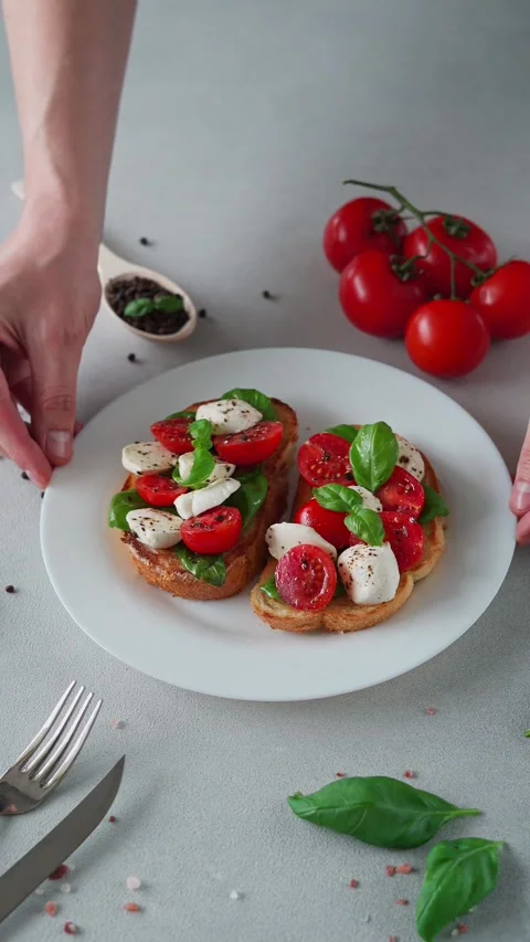 Bruschetta with tomatoes, mozzarella and basil leaves on light background Stock Footage 240103554