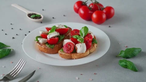 Bruschetta with tomatoes, mozzarella and basil leaves on light background Stock-Footage 240107965