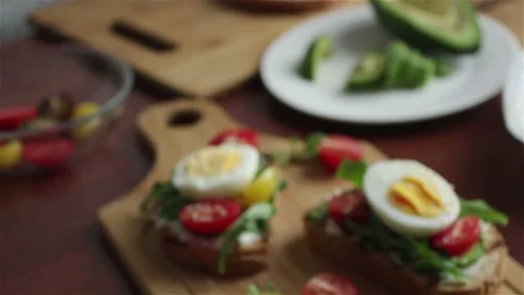 Bruschettas with avocado cherry tomatoes boiling egg arugula panning shot Stock Footage 105231260