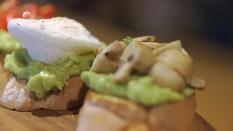 Bruschettas with avocado, poached egg and mushrooms on white bread, bruschetta Vidéo 256143428
