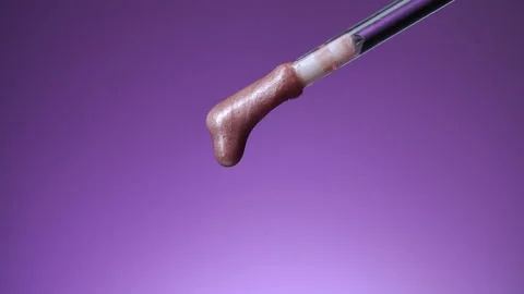 Brush and a slowly falling drop of lip gloss Stock Footage 166551025