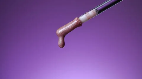 Brush and a slowly falling drop of lip gloss Stock Footage 166551076