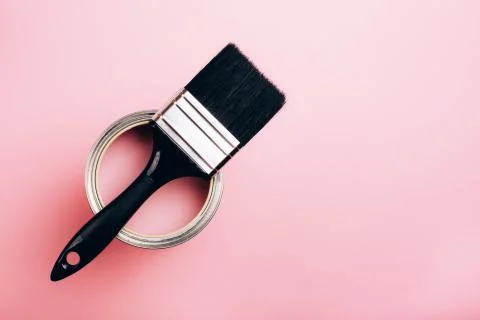 Brush with black handle on open can of pink paint on pastel background. Stock Photos