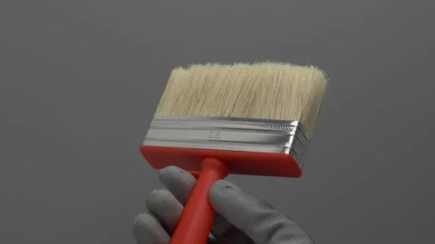 A brush for ceilings rotates in a hand on a gray background. Stockbeeldmateriaal 266892525