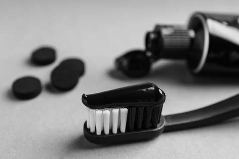Brush with charcoal toothpaste on light grey background, closeup Stock Photos