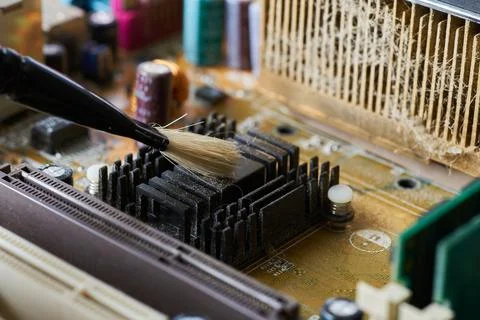 Brush cleaning an old computer board from dust and dirt. Close-up. Stock Photos