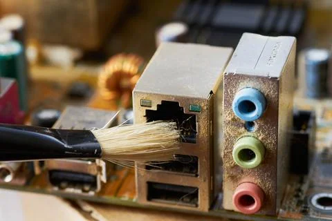 Brush cleaning an old computer board from dust and dirt. Close-up. Stock Photos