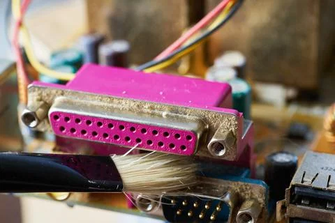 Brush cleaning an old computer board from dust and dirt. Close-up. Stock Photos