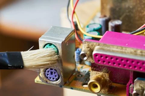 Brush cleaning an old computer board from dust and dirt. Close-up. Stock Photos