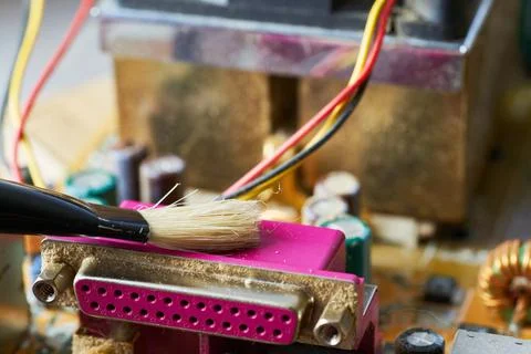 Brush cleaning an old computer board from dust and dirt. Close-up. Stock Photos