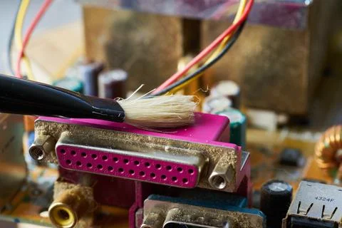 Brush cleaning an old computer board from dust and dirt. Close-up. Stock Photos