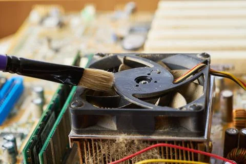 Brush cleaning an old computer board from dust and dirt. Close-up. Stock Photos
