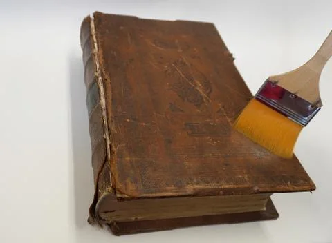 The brush cleans the corners of the binding of an old book. Stock Photos