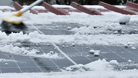Brush clears snow from solar panels.Removing snow from a roof with solar panels Stock Footage 317262383