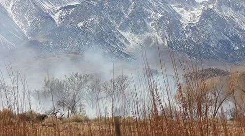 BRUSH FIRE AGAINST MOUNTAINS Stock Footage 10795554