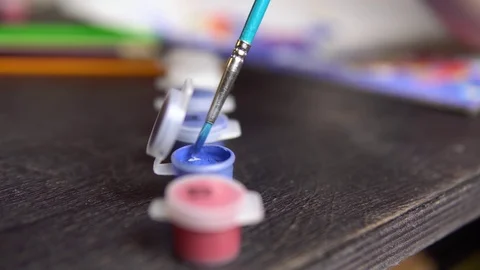 The brush is lowered into a jar of blue paint. Stock Footage 126424283