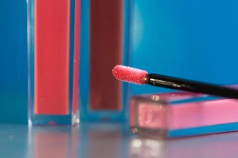 Brush for make-up lips and the bottle of liquid lipstick close-up on a blue b Stock Photos