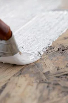 Brush paints flat surface with white paint against wood background Stock Photos