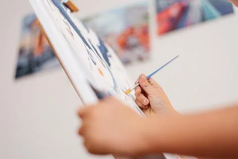 Brush with paints in the hands of a boy while drawing on canvas Stock Photos