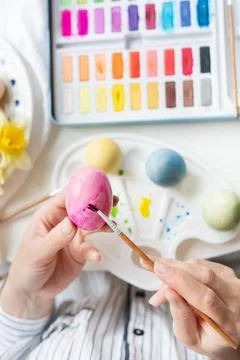A brush in the process of painting Easter eggs with watercolors. Top view, .. Stock Photos