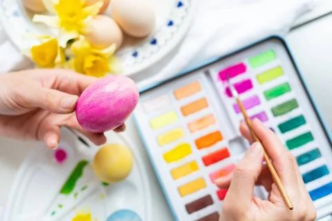 A brush in the process of painting Easter eggs with watercolors. The conce... Stock Photos
