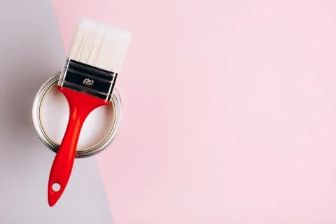 Brush with red handle on open can with pink paint on pastel background. Stock Photos