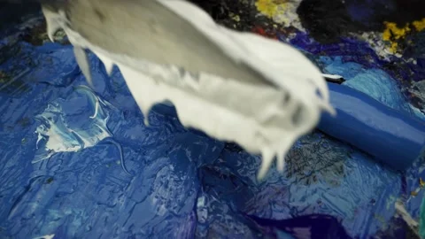 Brush stroke adds white paint to the blue paint squeezed from the tube layin Stock Footage 131831804