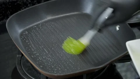 Brush the surface of the pan with oil using a silicone brush. Stock Footage 168637563