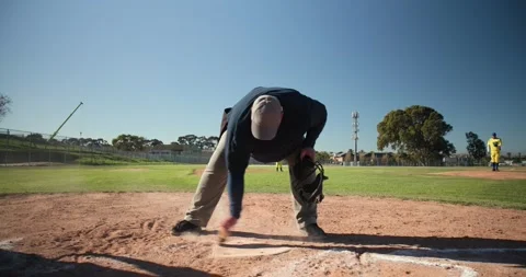 Brush sweeping chalk line at home plate, umpire donning face mask preparing to Stock Footage 340972282