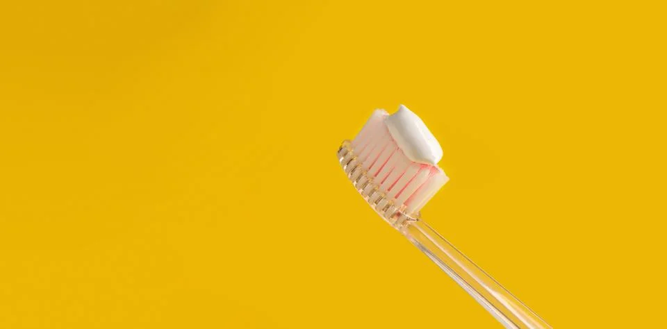 Brush with toothpaste on yellow background, space for text. Banner design Stock Photos