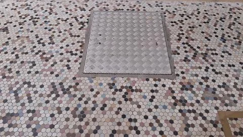 Brushed metal rectangular hatch plate centered on colorful hexagonal floor tiles Stock Photos