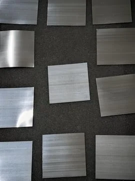 Brushed metal sample squares arranged on dark textured background pattern Stock Photos
