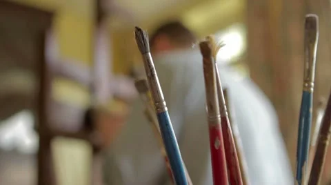 Brushes in artists's studio with soft focus artist in background 스톡 동영상 56169055