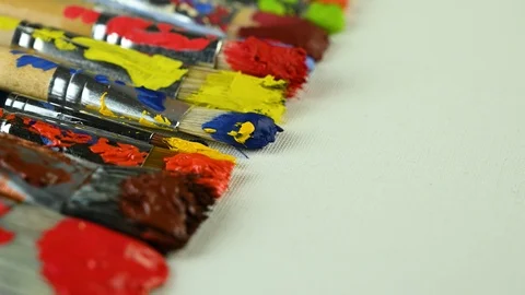 Brushes with different paints lie on canvas Stock Footage 124914581
