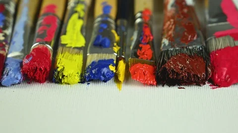Brushes with different paints lie on canvas Video stock 124914696
