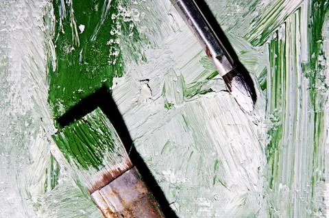 Brushes lie on canvas painted white green paint. Top view Stock Photos