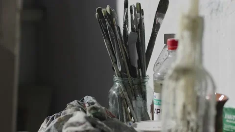Brushes paint thinner and molten candle in bottle on table Stock Footage 138638869
