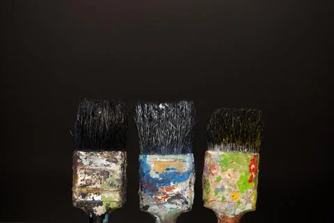 Brushes in paints on a black background Stock Photos