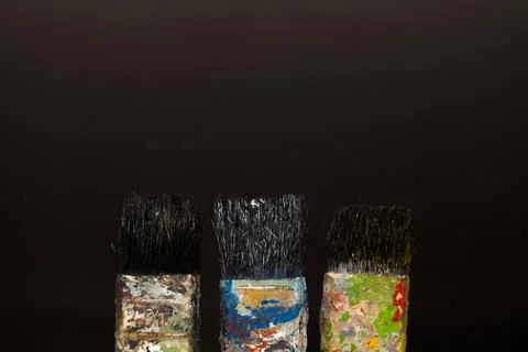 Brushes in paints on a black background Stock Photos