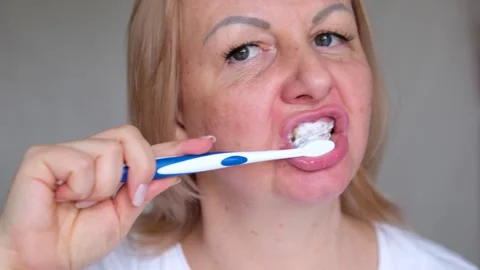 Brushes teeth Portrait of attractive lady brushing teeth near mirror Stock Footage 294181453