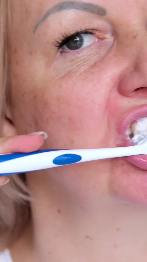 Brushes teeth Portrait of attractive lady brushing teeth near mirror Stock Footage 294343564