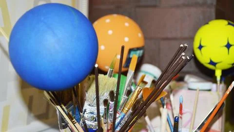 Brushes of various shapes, paint cans, and colorful decorative balls Stock Photos