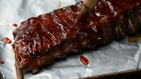 Brushing BBQ sauce on grilled rack of ribs on foil Stock Footage 242618575