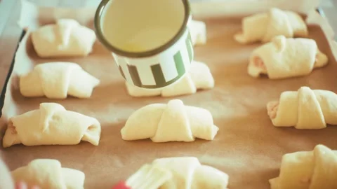 Brushing crescent rolls with milk close up, glazing homemade savory croissants Stock Footage 337877807
