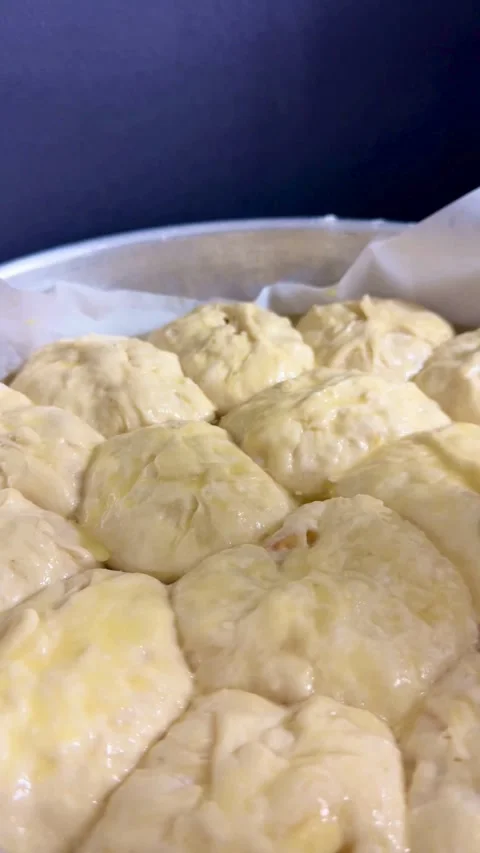 Brushing egg wash glaze onto raw yeast dough rolls Stock Footage 334592675
