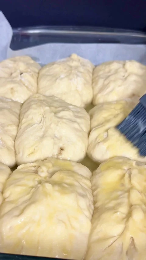 Brushing egg wash on raw dough buns before baking Stock Footage 331980881